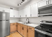Thumbnail 8 of 31 - A kitchen with a stainless steel refrigerator, microwave, and oven.
