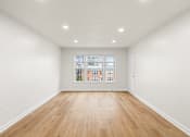 Thumbnail 18 of 31 - A room with wooden floors and a window showing a view of a building.