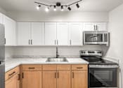 Thumbnail 7 of 31 - A kitchen with white cabinets and a black stove top oven.