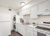 Thumbnail 6 of 31 - A white kitchen with a refrigerator, washing machine, dishwasher, and oven.