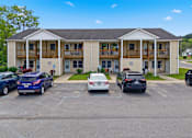 Thumbnail 27 of 30 - A carport with several cars parked in front of a two-story building.