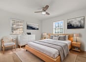 Thumbnail 7 of 28 - A bedroom with a bed, nightstand, chair, and two pictures on the wall.