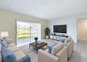 Thumbnail 2 of 25 - A living room with a couch, a coffee table, and a television.