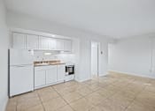 Thumbnail 18 of 26 - A kitchen with white appliances and cabinets.