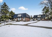 Thumbnail 4 of 17 - A snow-covered ground with a house and a tree in the foreground.