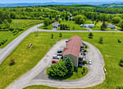 Thumbnail 48 of 53 - A large house with a red roof is surrounded by a grassy area and a winding road.