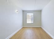 Thumbnail 11 of 16 - A room with a window and wooden flooring.