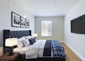 Thumbnail 6 of 16 - A bedroom with a bed, nightstand, lamp, and a flat screen TV mounted on the wall.