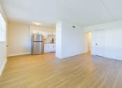 Thumbnail 9 of 16 - A kitchen with a refrigerator, sink, and cabinets is visible from the living room.