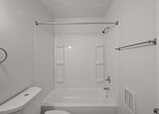 Thumbnail 11 of 16 - A white bathroom with a toilet, sink, and bathtub.