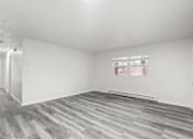 Thumbnail 7 of 16 - A room with a window and wooden flooring.