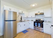 Thumbnail 1 of 16 - A kitchen with a stainless steel refrigerator and white cabinets.