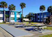 Thumbnail 9 of 12 - A blue and white building with a playground in front.