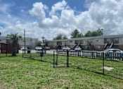 Thumbnail 8 of 17 - A black fence surrounds a grassy area in front of apartment buildings.