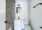Thumbnail 6 of 23 - A white toilet with a sink and mirror in a bathroom.