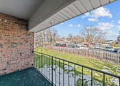 Thumbnail 23 of 29 - A balcony with a brick wall and a metal railing overlooking a parking lot.