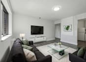 Thumbnail 5 of 41 - A modern living room with a black couch and a glass coffee table.