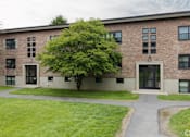 Thumbnail 43 of 49 - A tree is in front of a building with a grassy area in front of it.