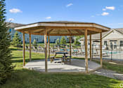Thumbnail 60 of 65 - A wooden pavilion with a picnic table sits in a grassy area.