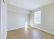 Thumbnail 8 of 16 - Empty room with wooden floor and white walls.