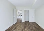 Thumbnail 8 of 23 - A room with white walls and wood flooring with two open doors.
