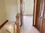 Thumbnail 22 of 53 - A hallway with a wooden staircase and a door on the right.