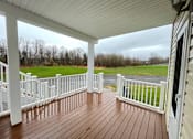 Thumbnail 32 of 53 - A wooden deck with a white railing and a view of a field.