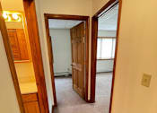 Thumbnail 23 of 53 - A hallway with a wooden door and a white wall.