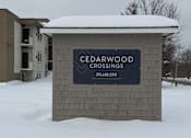Thumbnail 25 of 38 - A sign for Cedarwood Crossings stands in the snow.