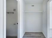 Thumbnail 5 of 23 - A white room with a door and a small vent on the wall.