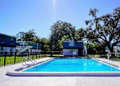 Thumbnail 14 of 16 - A swimming pool surrounded by trees and buildings.