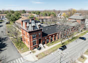 Thumbnail 33 of 41 - A large red brick building with a black roof and a tower with a dome on top.