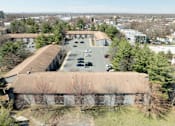 Thumbnail 34 of 41 - A parking lot is in front of a building with a brown roof.