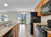 Thumbnail 25 of 55 - A kitchen with black appliances and granite countertops.