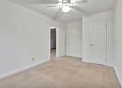 Thumbnail 12 of 25 - A room with a ceiling fan and carpeted floor.