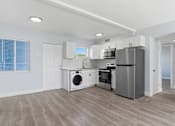 Thumbnail 9 of 18 - A modern kitchen with stainless steel appliances and wooden flooring.