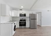 Thumbnail 12 of 18 - A kitchen with white cabinets and stainless steel appliances.