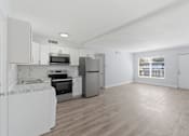 Thumbnail 11 of 18 - A kitchen with white appliances and wooden floors.