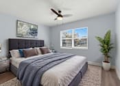 Thumbnail 3 of 18 - A bedroom with a bed, a ceiling fan, and a potted plant.
