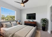 Thumbnail 5 of 18 - A bedroom with a large bed, a ceiling fan, and a flat-screen TV mounted on the wall.