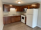 Thumbnail 14 of 49 - A kitchen with brown cabinets and white appliances.