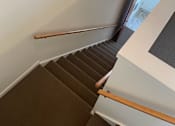 Thumbnail 33 of 49 - A staircase with a white wall and brown carpet.