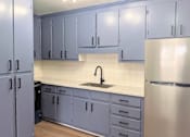 Thumbnail 2 of 15 - A kitchen with a sink and a refrigerator.
