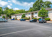 Thumbnail 14 of 16 - A parking lot with cars and apartment buildings in the background.