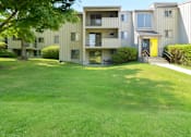 Thumbnail 10 of 18 - A grassy area in front of apartment buildings.