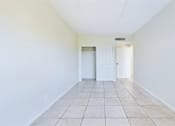 Thumbnail 13 of 25 - A long white hallway with a white door at the end.