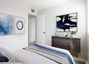 Thumbnail 2 of 12 - a bedroom with a bed and a dresser