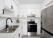 Thumbnail 1 of 12 - a kitchen with white cabinets and a sink and a stove