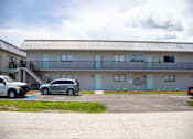 Thumbnail 11 of 16 - a building with a parking lot and cars in front of it