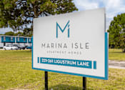Thumbnail 16 of 16 - a sign for marina isle apartment homes in front of a field